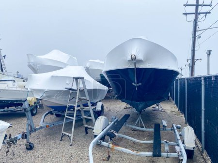 Photo for Boat on trailers shrink wrapped with white covers for their protection over the winter. - Royalty Free Image