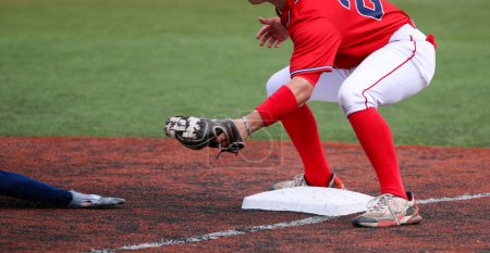 Téléchargez les photos : Troisième joueur de base prêt à marquer le bras d'un coureur coulissant lors d'un match de baseball au lycée. - en image libre de droit