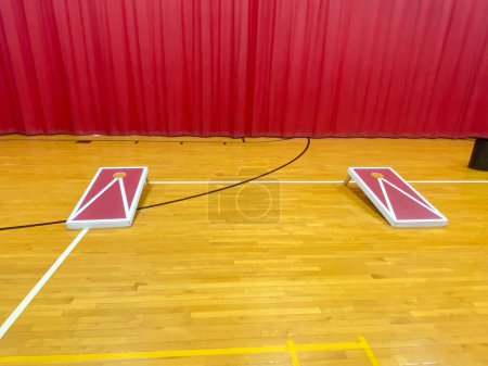 Photo for Front view of two homemade cornhole boards on a high school gym floor with a red curtain in the background. - Royalty Free Image