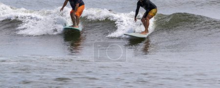 Photo for Front view of two men riding the same wave while surfing at Giglo Beach in Babylon Long Island New York. - Royalty Free Image