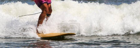 Photo for Close up of legs of a surfer on a yellow board at the end of his ride with a lot of white water. - Royalty Free Image