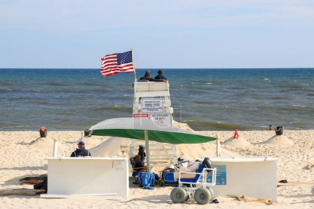 Photo for Gilgo Beach, New York, USA - 13 August 2023: Rear view of A lifeguard chair on the beach with an american flag blowing in the wind - Royalty Free Image