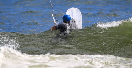 Photo for Man in the ocean holding a white board and a rope ready to be pulled up by a kite to kiteboard ride. - Royalty Free Image