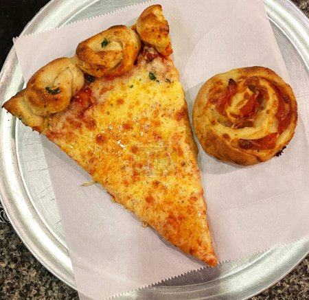 A slice of pizza and a pastry are neatly arranged on a white plate, showcasing a delicious meal option with contrasting flavors and textures. The golden-brown pastry complements the cheesy and savory slice of pizza