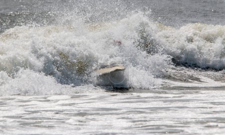 All you can see after a surfer wips out is his Surfboard in rough water after surfer wipes out and falls.