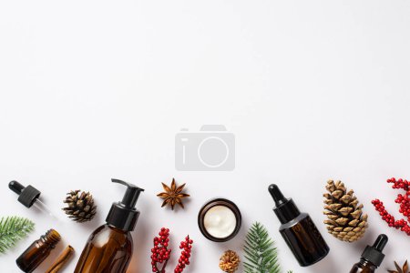 Photo for Natural cosmetics concept. Top view photo of amber glass pump bottle cream jar dropper bottle mistletoe berries spruce branches pine cones and anise on isolated white background with copyspace - Royalty Free Image