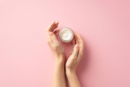Photo for Skin care concept. First person top view photo of young woman's hands and small jar of cream on isolated pastel pink background - Royalty Free Image