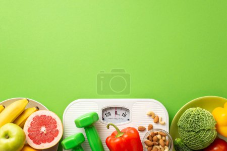 Photo for Slimming concept. Top view photo of plates with fruits and vegetables grapefruit apple bananas pepper cabbage cucumber nuts dumbbells and scales on isolated green background with copyspace - Royalty Free Image