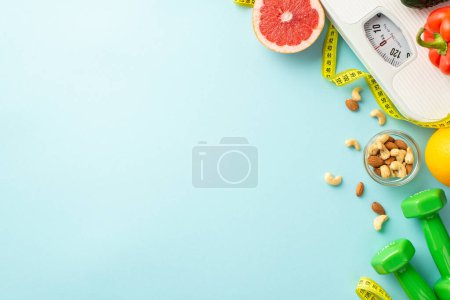 Photo for Weight loss concept. Top view photo of scales grapefruit sweet pepper almonds cashew dumbbells and tape measure on isolated pastel blue background with empty space - Royalty Free Image