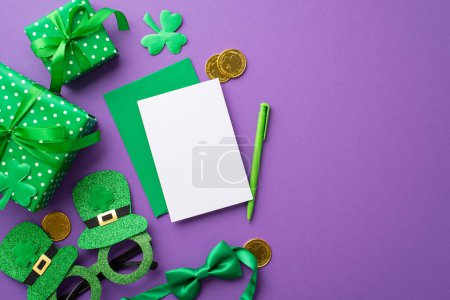 Concept de la Saint Patrick. Vue du dessus photo de boîtes-cadeaux vertes avec des arcs enveloppe papier feuille stylo chapeau en forme de lunettes de fête noeud papillon pièces d'or et des trèfles sur fond lilas isolé avec copyspace
