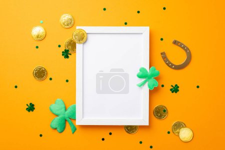 Photo for Saint Patrick's Day concept. Top view photo of empty photo frame horseshoe gold coins shamrocks and trefoil shaped confetti on isolated orange background with copyspace - Royalty Free Image
