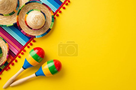 Photo for Cinco-de-mayo carnival concept. Top view photo of sombrero hats colorful striped serape and couple of maracas on isolated vivid yellow background with blank space - Royalty Free Image