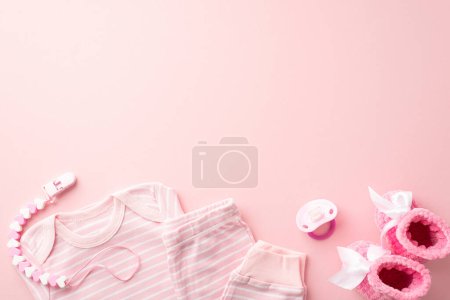 Babyzubehör-Konzept. Foto von oben von rosa Säuglingskleidung Hemdhosen-Schnullerkette und gestrickte Booties auf isoliertem pastellrosa Hintergrund mit Leerraum