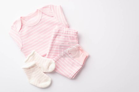 Babyduschkonzept. Foto von oben von rosa Säuglingskleidung Hemdhosen und Socken auf isoliertem weißen Hintergrund
