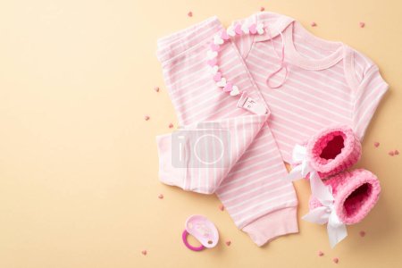 Babymädchenkonzept. Foto von oben von Säuglingskleidung rosa Hemdhosen gestrickte Booties Beißattrappe Kette und streut auf isolierten pastellgelben Hintergrund mit leeren Raum