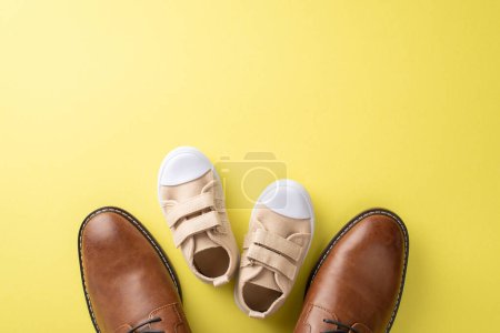 Den Vatertag mit Vater und Sohn feiern. Ansicht von Lederschuhen und Baby-Turnschuhen auf gelbem Hintergrund mit Leerraum für Werbung oder Nachricht