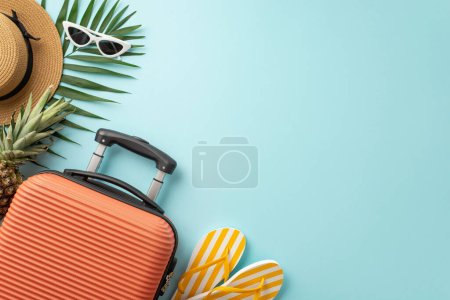 Photo for Summer escape to paradise. Overhead shot of orange suitcase, beach essentials, sunglasses, sunhat, flip-flops, ananas and palm leaves on a pastel blue background, perfect for text or promotions - Royalty Free Image