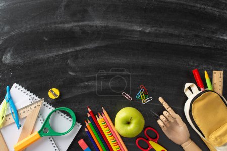 Immerse yourself in classroom aesthetic with top-down image: blackboard adorned with color pencils, notepads and array of stationery on isolated background, offering copyspace for adverts or text