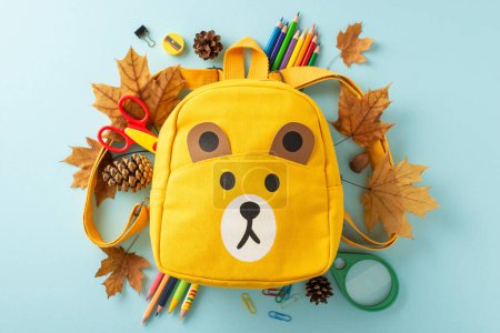 Photo for Step into the new school year with this captivating top-view image featuring cartoon yellow backpack, autumnal attributes and a variety of school supplies on a pastel blue backdrop - Royalty Free Image