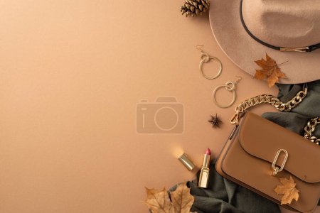 Klassisch weibliche Kleidung mit herbstlichem Touch. Draufsicht auf Krempe, grauen Schal, Handtasche, goldene Ohrringe, Lippenfarbe, verstreute Blätter, Anis, Tannenzapfen auf beigem Hintergrund mit Leerfläche für Text oder Werbung