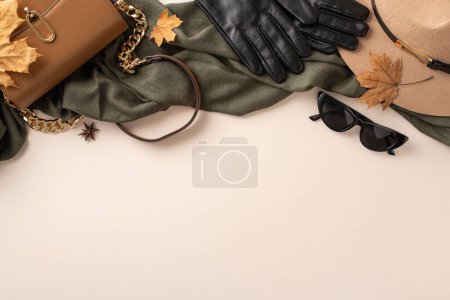 Téléchargez les photos : Vêtements et accessoires automnaux féminins concept. Au-dessus de l'image vue du dessus de coûteux sac à main en cuir gants sombres lunettes casque et écharpe verte sur fond beige clair espace vide pour le message - en image libre de droit