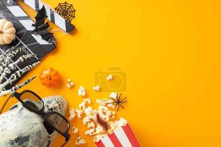 Photo for Embrace Halloween vibes with cinema top view featuring spooky elements like skeleton hand, skull in eyeglasses, creepy crawlies, bat, web, clapboard. Perfect for promoting ghostly movie night or event - Royalty Free Image