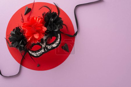 Foto de Vibrante máscara de carnaval Día de los Muertos cuenta con delicados encajes esqueleto, adornado con flores, plumas y corazones de papel sobre el círculo rojo. Vista superior de la superficie de color púrpura pastel, listo para la incorporación de texto - Imagen libre de derechos