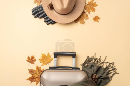 Téléchargez les photos : Échapper à la mode. Perspective aérienne d'une valise grise, d'une écharpe en cachemire, de feuilles d'automne, d'un chapeau en feutre confortable et de gants sur fond beige, offrant de l'espace pour votre contenu promotionnel ou votre texte - en image libre de droit