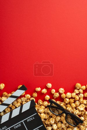 Vertical top view of vibrant red background adorned with popcorn, 3D glasses, and a clapperboard - a perfect canvas for your movie-themed text or promotional material
