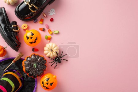 Téléchargez les photos : Plongez dans le plaisir d'Halloween avec cet ensemble de costumes délicieux pour les filles. Vue de dessus des petites mocassins en cuir, chapeau enchanteur, maïs bonbon et décor sur un décor rose pastel. Annoncez efficacement ici - en image libre de droit