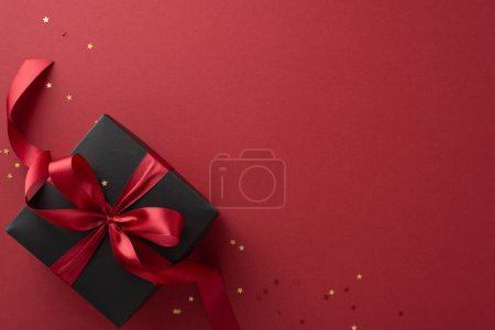 Téléchargez les photos : Élevez vos promotions Black Friday avec cette image exquise vue de dessus boîte cadeau noir orné d'un ruban rouge vibrant, complété par des confettis en forme d'étoile d'or, sur un fond de marsala - en image libre de droit