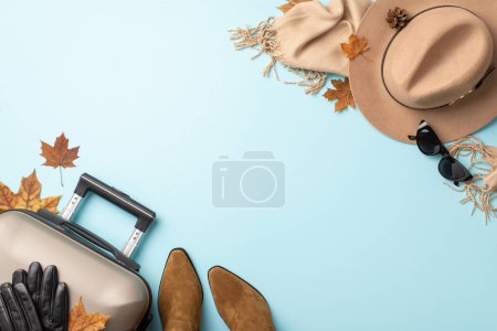 Téléchargez les photos : Détendez-vous dans la sophistication cet automne. Plan grand angle avec valise grise, écharpe confortable, lunettes de soleil à la mode, bottes et chapeau en feutre sur une surface bleu clair, conçu pour vos besoins promotionnels ou textuels - en image libre de droit
