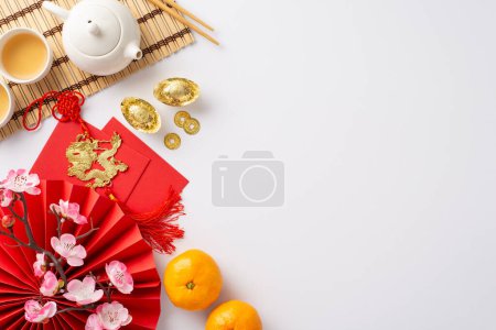 Photo for Immerse in richness of Chinese New Year with exquisite table setting. Top-view image showcasing traditional fan, green tea ceremony set, Feng Shui artifacts, sakura, etc, white backdrop for advert - Royalty Free Image
