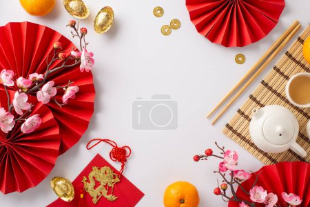 Photo for Lunar New Year Dining Setup: Top view fans, tea ceremony set, coins, sycee, lucky red envelopes, dragon charm decor, fruits, sakura on white backdrop. Advertise with this vibrant festive composition - Royalty Free Image