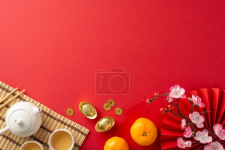Photo for Chinese New Year Banquet Scene: Overhead shot featuring fan, tea ceremony items, bamboo placemat, traditional coins, sycee, Hong Bao, tangerines, sakura on red background. Ideal for festive promo - Royalty Free Image
