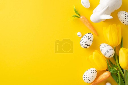 Ostern kreative Anzeige: Draufsicht auf vereinfachend gefärbte Eier, entzückende Hasenfigur, Zuckerbrot und frische Tulpen auf leuchtend gelber Leinwand, mit Platz für Text oder Werbung
