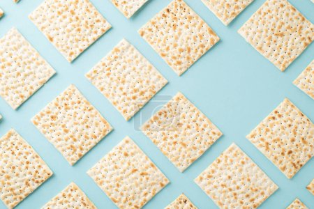 Seder night motif: Top view snapshot of neatly arranged matza, leaving one spot open for text on a soft blue backdrop
