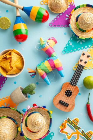 Foto vertical que captura la esencia del Cinco de Mayo con sombreros, maracas, vihuela, cactus, banderas, lima y nachos, todo sobre una suave superficie azul. Patrón Cinco de Mayo