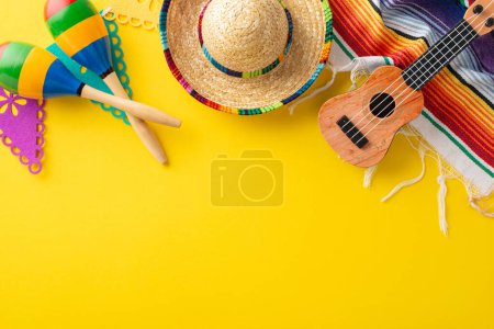 Festive setup for Cinco de Mayo. Top-view photo showcasing traditional decor: hat, guitar, maracas, striped blanket, pennant flags, served on yellow, with blank space for copy