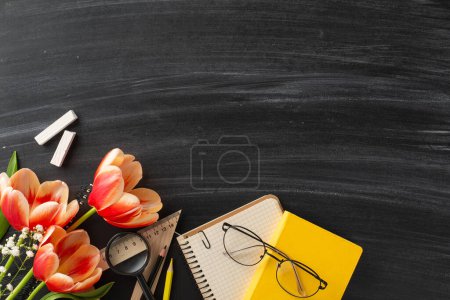 Photo for Commemorate stylish Teacher's Day idea. Overhead shot of academic tools, notebooks, pencils, chalk, spectacles, and colorful tulips on chalkboard surface, offering space for messages or advertisements - Royalty Free Image