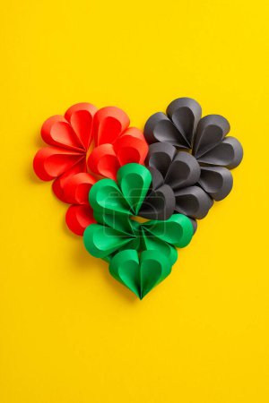 Photo for A vibrant vertical display of paper hearts in red, green, and black, arranged on a yellow background, symbolizing Juneteenth and the spirit of freedom - Royalty Free Image