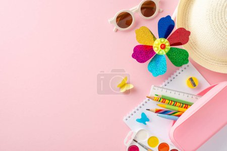 Téléchargez les photos : Des outils éducatifs estivaux dynamiques pour les enfants, y compris un moulinet coloré, des fournitures scolaires et un chapeau de paille étalé sur un fond rose, symbolisant un apprentissage amusant - en image libre de droit