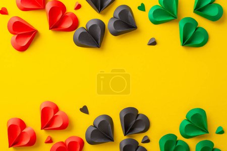 A vibrant display of red, black, and green paper hearts scattered on a yellow surface, representing the Juneteenth celebration and the themes of freedom and unity