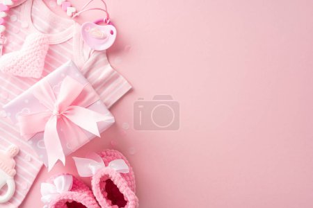 A pink-themed baby shower gift set, including clothes, knitted heart, pacifier, rattle, and a gift box with a ribbon