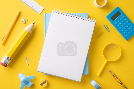 Top view of vibrant school supplies including notebook, pencil, calculator, ruler, and paper clips on a bright yellow background