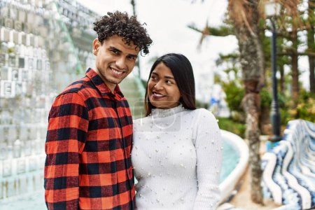 Téléchargez les photos : Jeune couple latin souriant heureux et câlin à la ville. - en image libre de droit