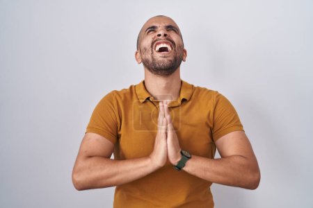 Téléchargez les photos : Hispanic man with beard standing over white background begging and praying with hands together with hope expression on face very emotional and worried. begging. - en image libre de droit