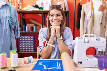 Photo for Hispanic young woman dressmaker designer at atelier room laughing nervous and excited with hands on chin looking to the side - Royalty Free Image