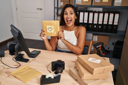 Foto de Mujer hispana joven que trabaja en el comercio electrónico de pequeñas empresas sonriendo y riendo en voz alta porque divertida broma loca. - Imagen libre de derechos