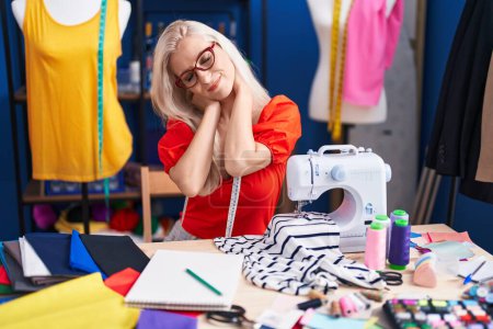 Téléchargez les photos : Young blonde woman tailor stressed using sewing machine at sewing studio - en image libre de droit